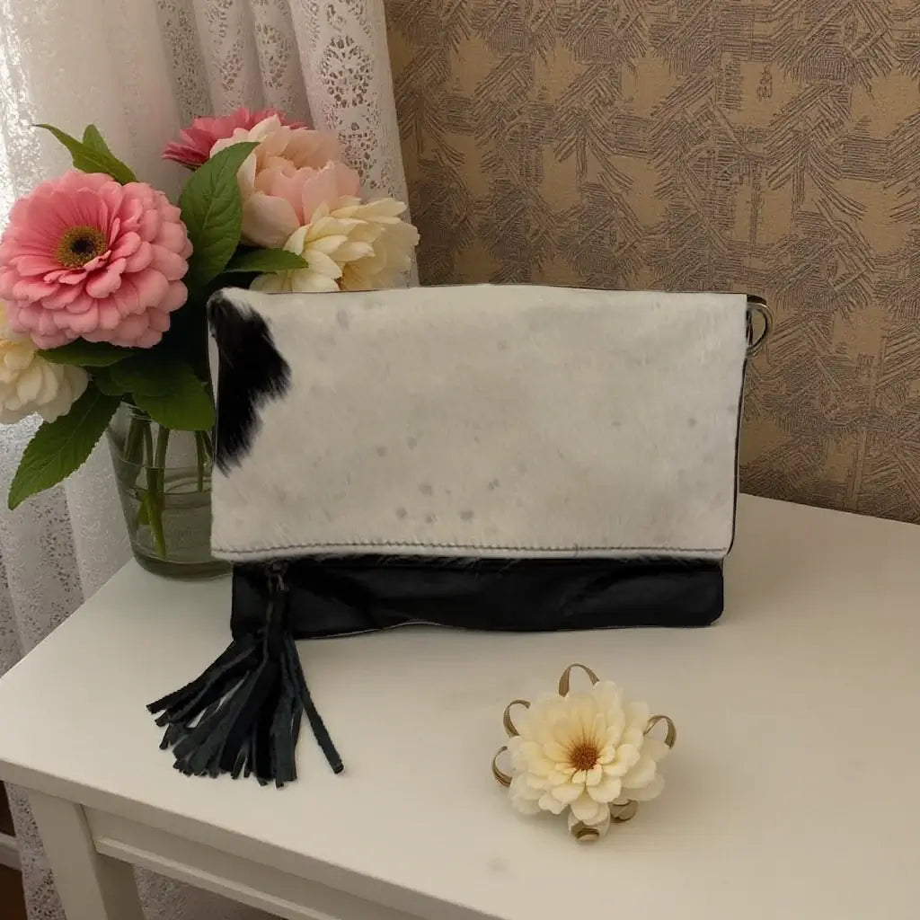 Cowhide Clutch Crossbody with Tassel featuring a black-and-white pattern and leather tassel zipper detail.