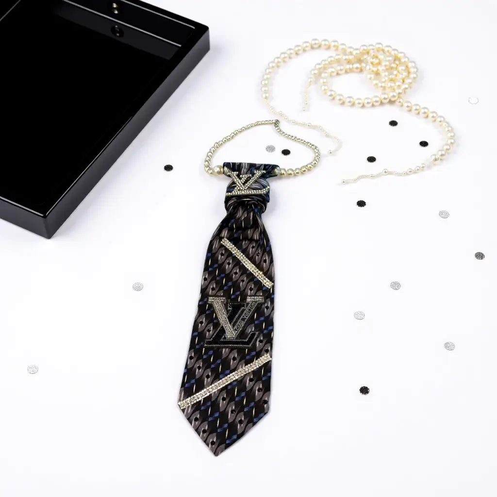 Legacy Luxe Noir Monarch Tie elegantly displayed with pearls and confetti on a white background.