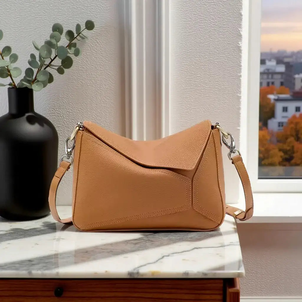 Geometric Shoulder Bag displayed on a marble surface with a vase and city view in the background, showcasing its structured design.