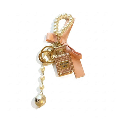 Legacy Luxe Pearl Parfum Charm featuring a gold parfum pendant, pearl accents, and soft satin bow.