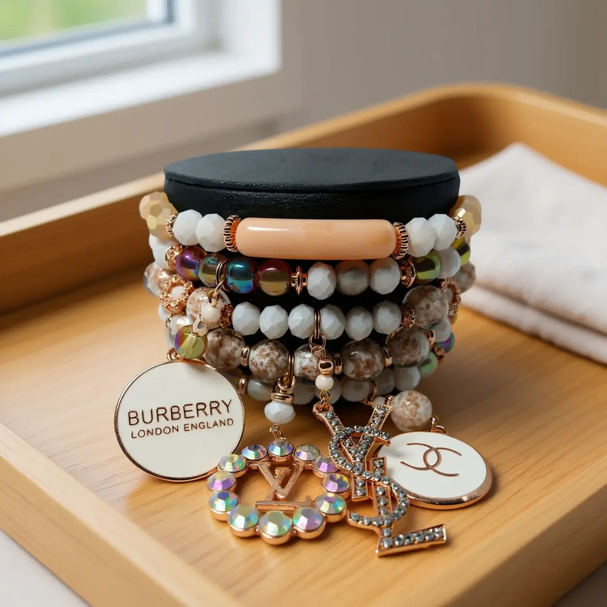 A stylish stack of bracelets featuring earthy tones and luxurious charms on a display, showcasing elegant jewelry design.