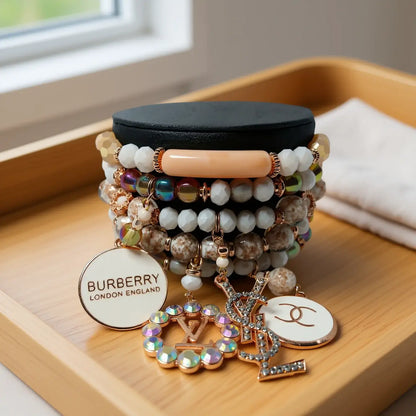 A stylish stack of bracelets featuring earthy tones and luxurious charms on a display, showcasing elegant jewelry design.