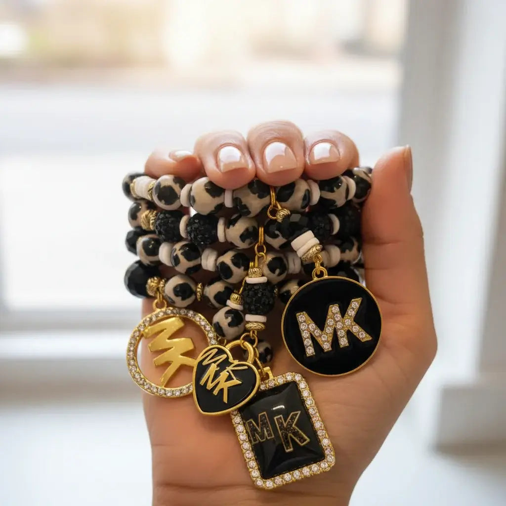 A hand holding multiple Legacy Ebony Ivory Duo Gem Set bracelets with black, white, and gold accents.
