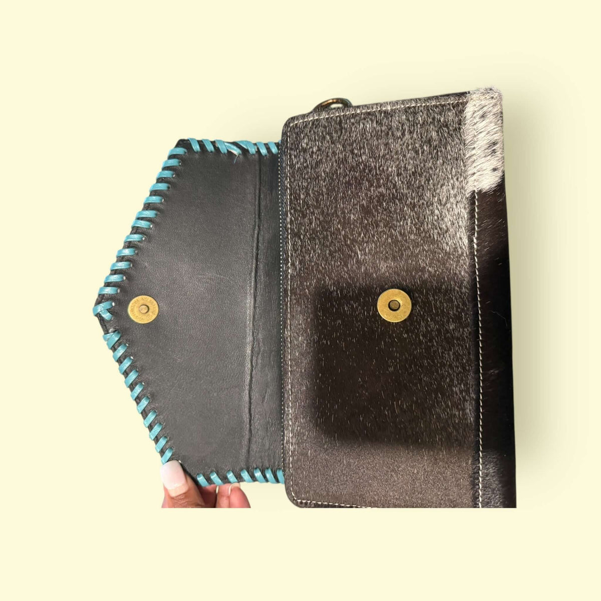 Interior view of Bloom Cowhide Crossbody Wallet showcasing turquoise whipstitch detailing and genuine cowhide craftsmanship.